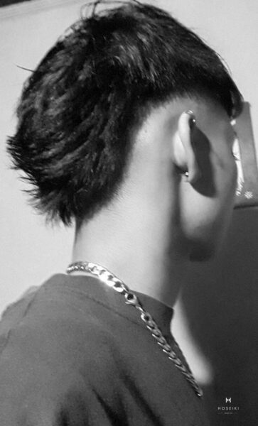 Chàng trai trẻ với tóc Mohican chéo màu nâu sáng đứng trước cửa sổ