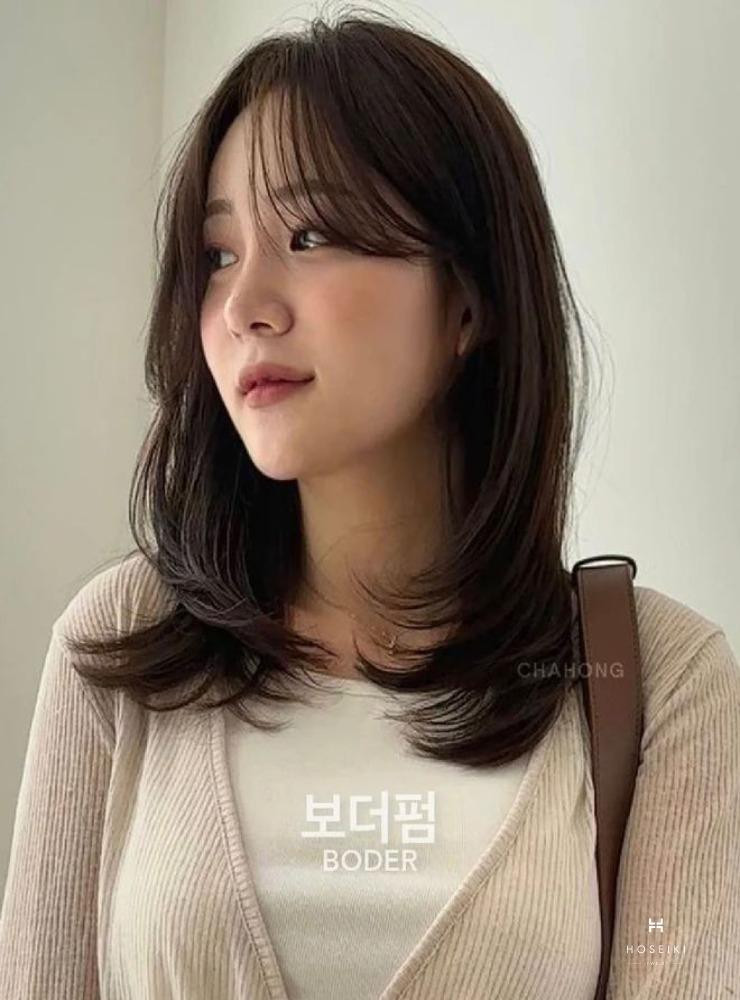 Một cô gái với mái tóc layer ngang vai hơi uốn nhẹ phần đuôi, giúp gương mặt trông dài và thanh thoát hơn.